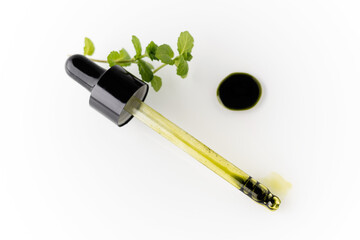 Liquid chlorophyll extract in a package and clean water with a mint leaf on a white background. The concept of superfoods, healthy eating, detox and wellness