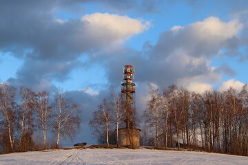 Obraz premium Nisanka lookout tower in the Jizera Mountains. Snowy landscape with clouds