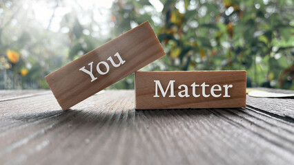 You matter text on wooden blocks with bright sun and park background.