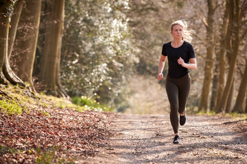Young Woman Running In Autumn Countryside To Improve Mental Health During Health Lockdown