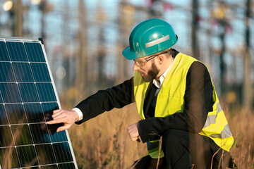 Electric engineer checking photovoltaic solar panels wearing helmet suit and safety vest Concept...