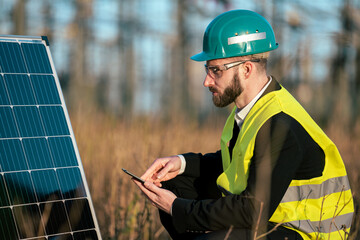 Electric engineer checking photovoltaic solar panels wearing helmet suit and safety vest Concept...