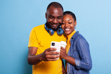 Smiling people taking pictures on smartphone camera, laughing and enjoying romantic moment. Positive couple making memories with selfies and expressing affection for each other.