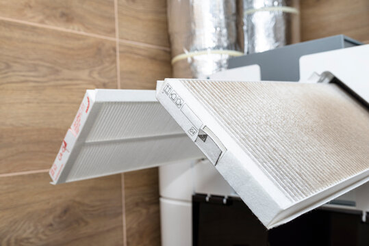 Home mechanical ventilation with heat recovery hanging on the wall, visible dirty G4 filter and clean F7 filter sticking out of the machine.