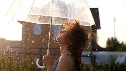 Happy young woman dancing and having fun with umbrella outdoor at sunny weather