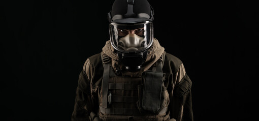 a man in a military uniform and a gas mask holds with an angry expression of emotions on a black background