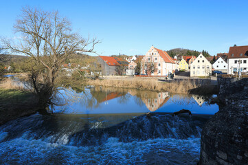 Blick &uuml;ber die historische Steinbr&uuml;cke &uuml;ber den Fluss W&ouml;rnitz in Harburg in Schwaben, bei strahlend blauem Himmel im Winter. Bayern, Deutschland, 