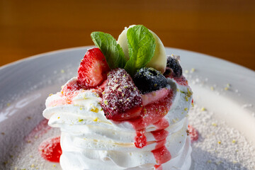Pavlov dessert with whipped whites and berries on a white plate