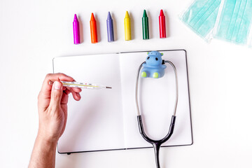Pediatrics equipment with crayons, copybook white background top view space for text