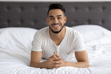 Portrait Of Handsome Smiling Young Arab Man Relaxing On Bed At Home
