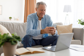 Portrait of smiling mature man using smartphone at home