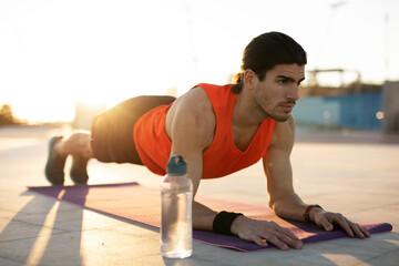 Young muscle man training outside. Fit handsome man doing exercise..