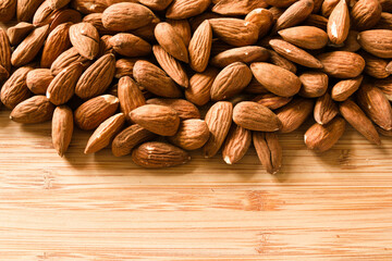 Group of almonds isolated on wooden background, top view with copy space