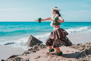 Woman with flower necklace on the beach.  Lady dancer dancing hula dance dressed in tropical outfit. Hawaiian woman enjoys hula dancing on the beach barefoot wearing traditional costume - obrazy, fototapety, plakaty