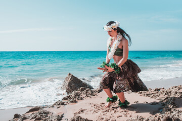 Hawaiian woman enjoys hula dancing on the beach barefoot wearing traditional costume