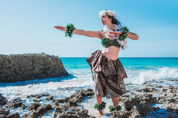 Hawaiian woman enjoys hula dancing on the beach barefoot wearing traditional costume - obrazy, fototapety, plakaty