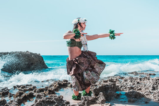 Hawaiian woman enjoys hula dancing on the beach barefoot wearing traditional costume. Hula dancer lady dancing Hawai dance.