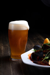 beer with mussels in tomato sauce with microgreens and lemon, on a wooden background