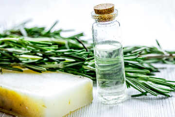 cosmetic oil in bottle with herbs on light table background