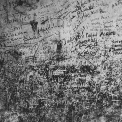 Texture of old wall with inscriptions. Text on the wall in a black and white photo. Grunge background. Ancient worn wall backdrop with letters and graffiti.