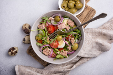 Healthy tuna salad with fresh arugula, cherry tomatoes, quail egg and olives