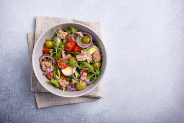 Healthy tuna salad with fresh arugula, cherry tomatoes, quail egg and olives