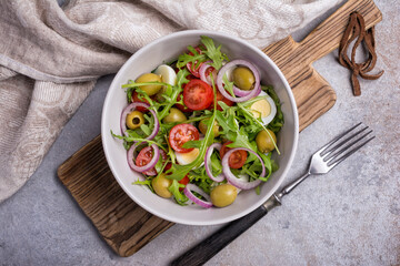 Healthy vegetarian salad with fresh arugula, cherry tomatoes, quail egg and olives