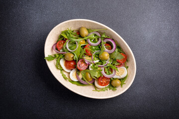 Healthy vegetarian salad with fresh arugula, cherry tomatoes, quail egg and olives