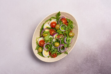 Healthy vegetarian salad with fresh arugula, cherry tomatoes, quail egg and olives