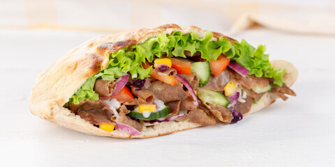 Döner Kebab Doner Kebap slice fast food in flatbread on a wooden board panorama