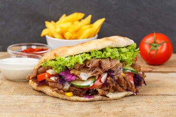 Döner Kebab Doner Kebap fast food in flatbread with fries on a wooden board