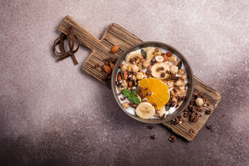 Healthy breakfast of granola with nuts, banana, orange and yogurt