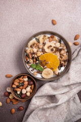 Healthy breakfast of granola with nuts, banana, orange and yogurt