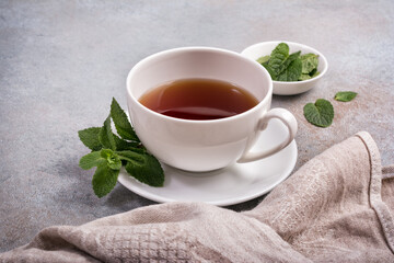Cup with tea and green fresh mint leaves