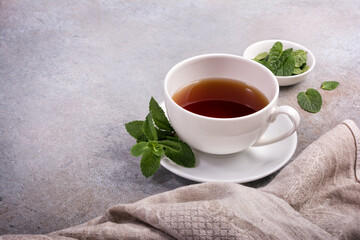 Cup with tea and green fresh mint leaves