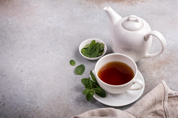 Cup of tea with teapot and green fresh mint leaves