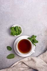 Cup with tea and green fresh mint leaves