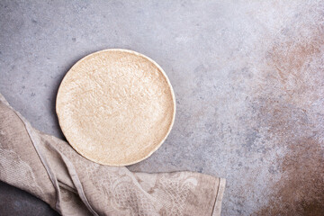 Empty ceramic plate with linen napkin on concrete
