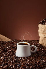 White cup with coffee beans on dark background