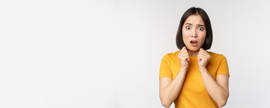 Portrait Of Scared Asian Woman Shaking From Fear, Looking Terrified And Concerned, Standing Anxious Against White Background