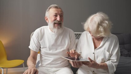 Elderly Caucasian man and woman play online games, look at the screen. - Powered by Adobe