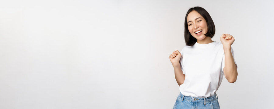 Happy Dancing Korean Girl Posing Against White Background, Wearing Tshirt