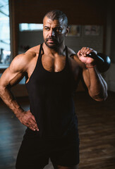 Close up portrait of African American muscular man lifting a kettlebell at gym.