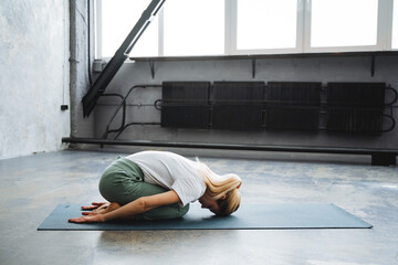 A blonde girl does yoga lying on a mat. Take mudra yoga , tuning the asana on the floor.Perform...