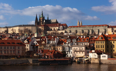 Obraz premium Prague Castle and its neighborhood. The cathedral the castle and the historic districts all around under the sun. The sky has a few clouds.