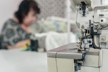 Blurred photo of professional modern dressmaker working on sewing machine