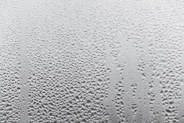 Steamy window with water drops made in dull day, condensation on glass with drops flowing down, humidity and foggy blank