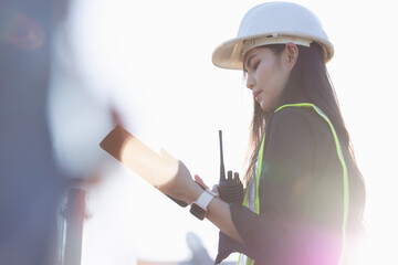 Asian engineer woman or architect looking forward with white safety helmet in construction site. Standing at modern building construction. Worker asian woman working project building