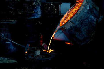 The red-hot metal flows out of the bucket and is poured into special molds. Soft focus