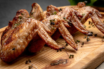 fried chicken wings on a wooden board on a dark background